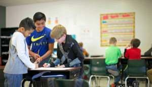 Students are working together in a project-based learning classroom that uses Summit Learning as an educational resource and tool.